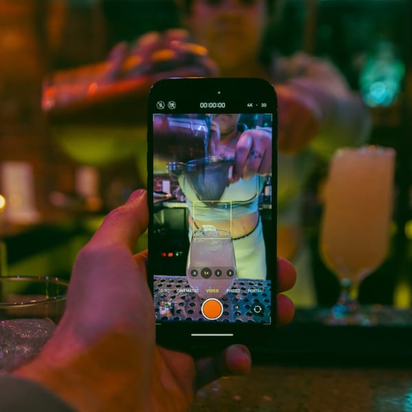 A person records a bartender pouring a cocktail into a glass at Tipsea bar.