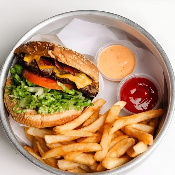 A Tipsea bacon cheeseburger with lettuce and tomato, fries, ketchup, and special sauce in a metal tray.